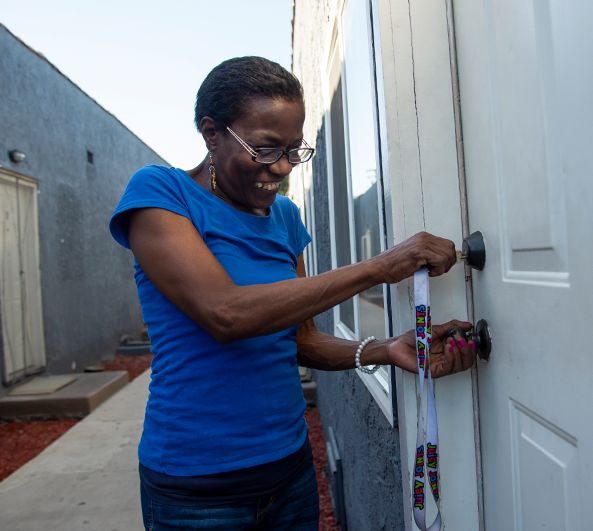 A resident smiling as she unlocks the door to her home